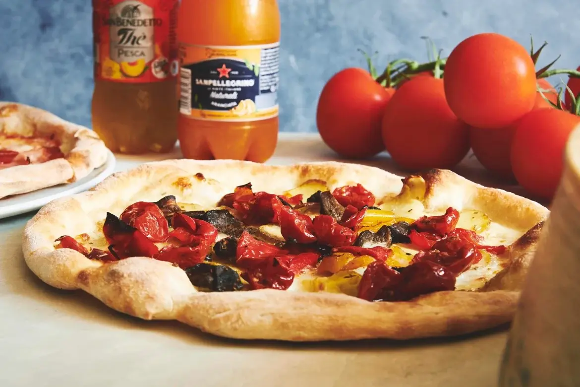Nybagt pizza med bagte tomater og grøntsager på Basilico
